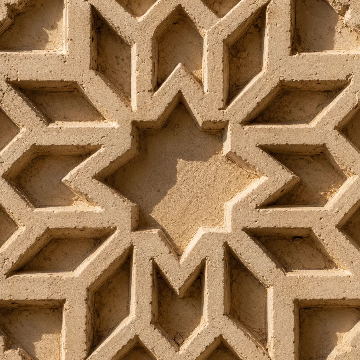 Raking light across an eight-point seal star carved into plaster.